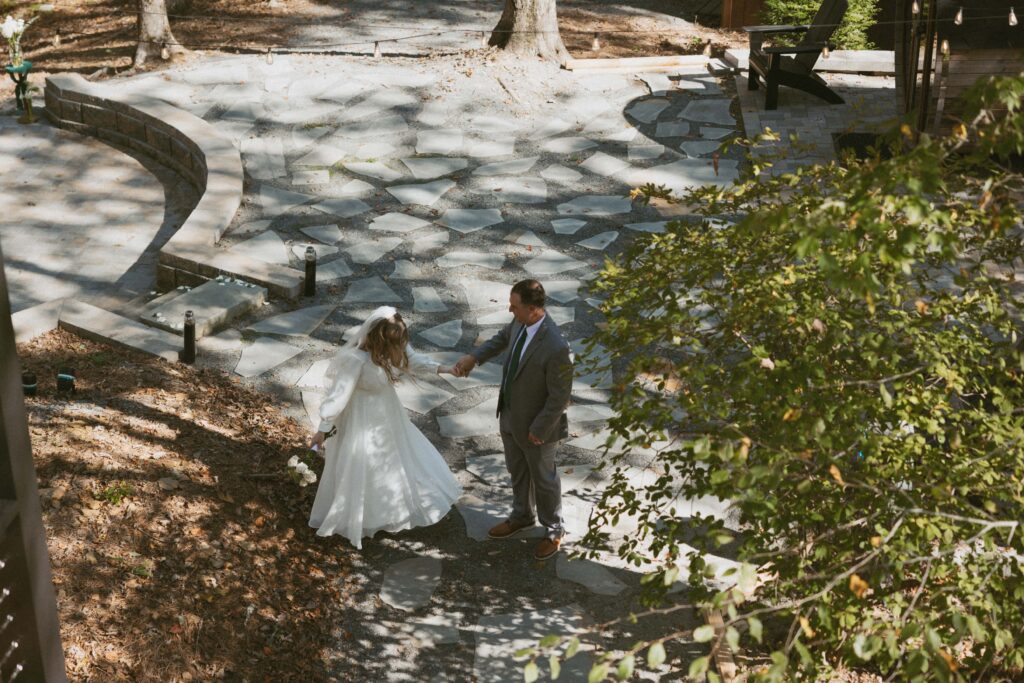 Man and woman in wedding attire dancing on sidewalk of Airbnb.