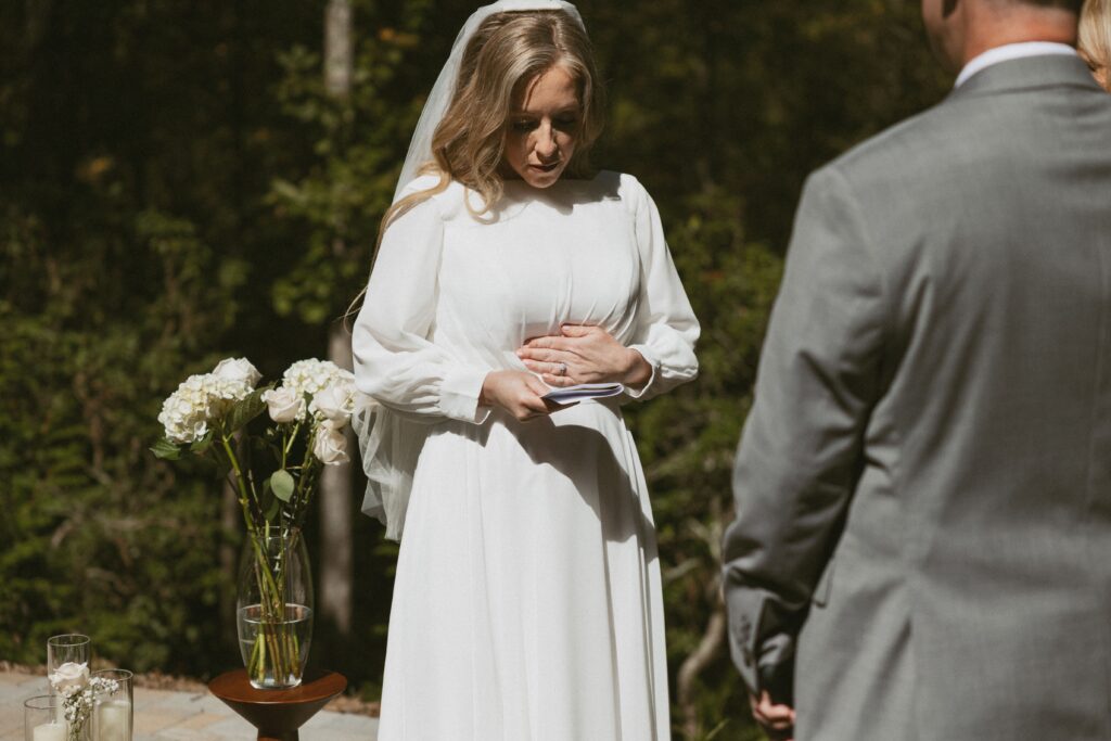 Woman in wedding dress reading vows to man in suit.