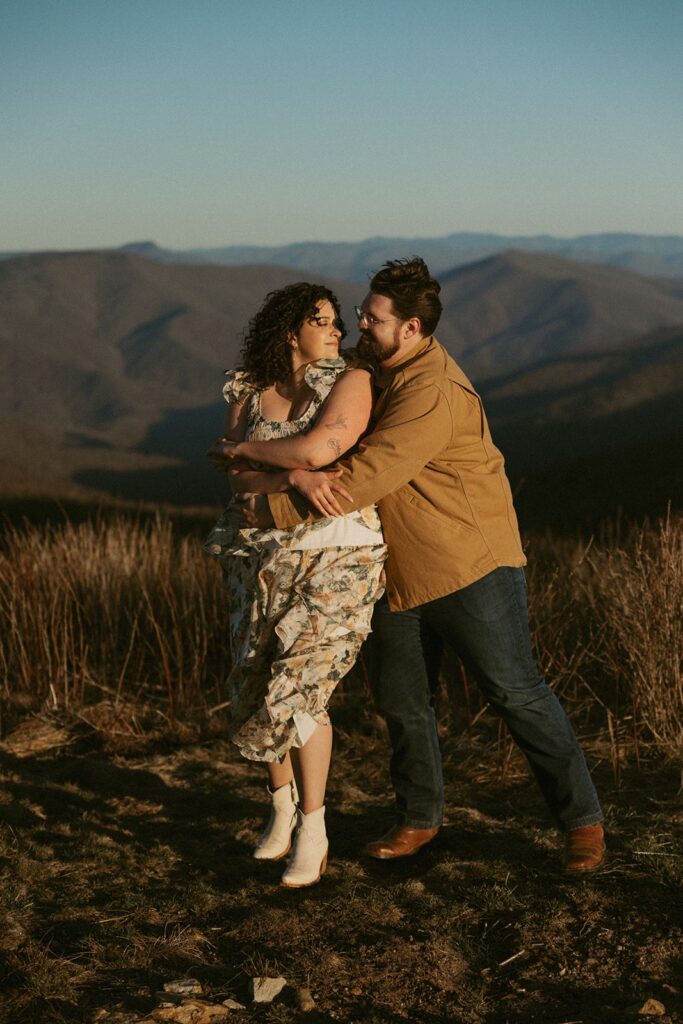 Man and woman dancing and smiling at each other with mountains behind them.