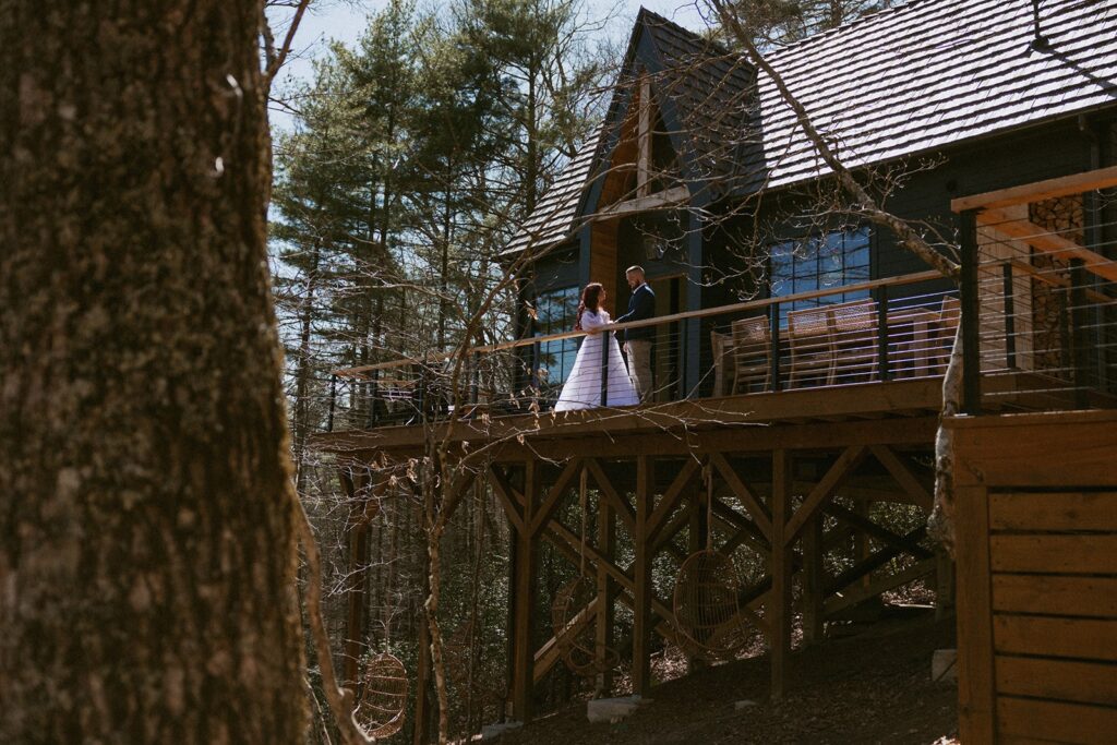 Man and woman in wedding attire standing on deck of Airbnb in Highlands nc.