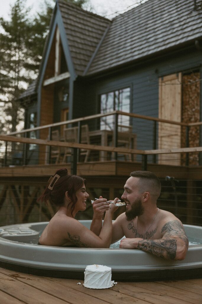 Man and woman in hot tub eating a small cake.