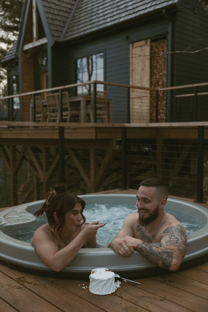 Man and woman in hot tub eating a small cake.