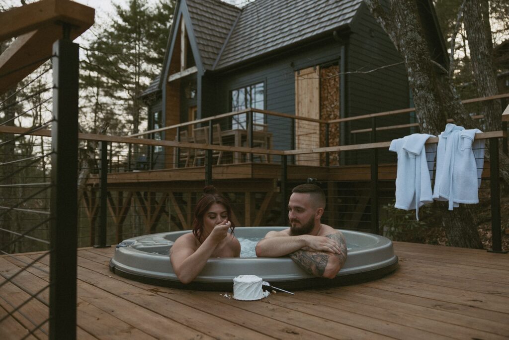 Man and woman in hot tub eating a small cake.