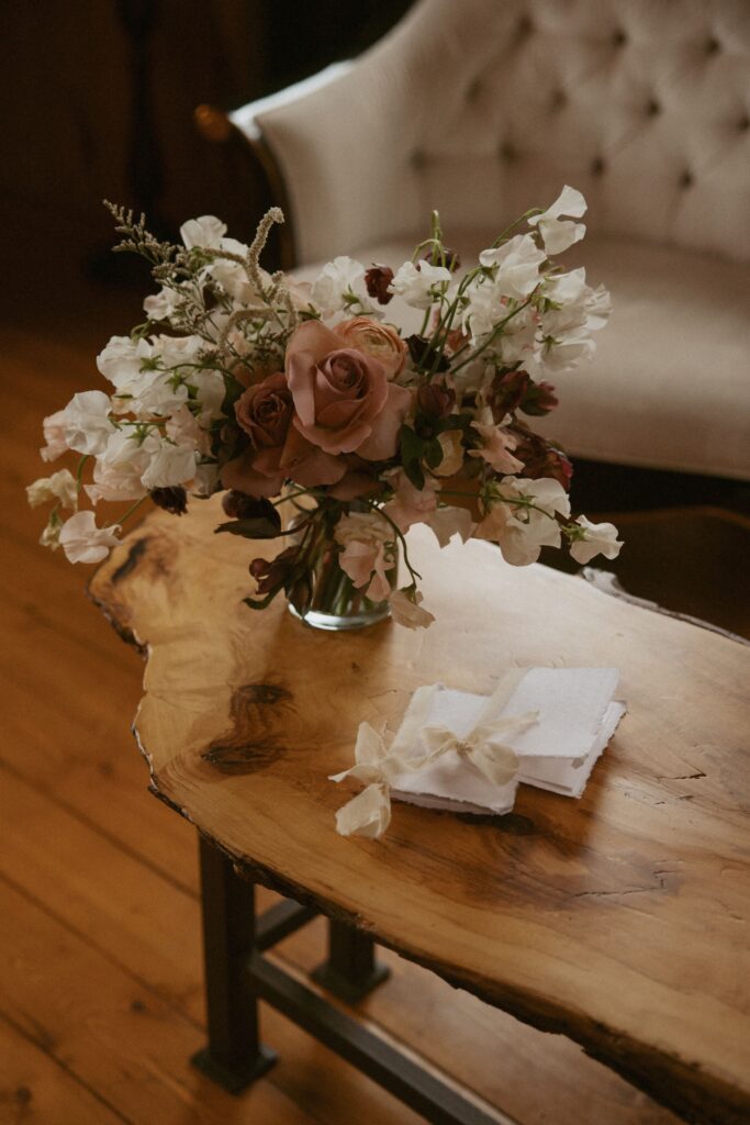 Bouquet and vow books sitting on a wooden bench in a cabin.