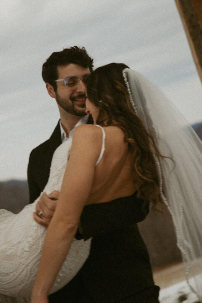 man cradling woman in wedding dress and spinning her.