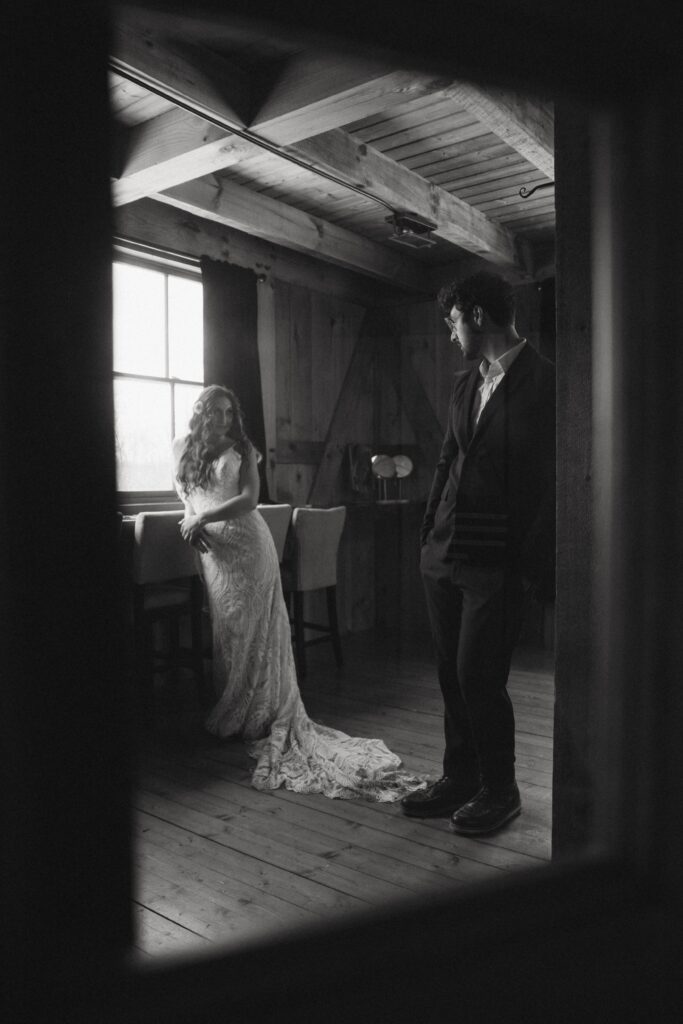 man and woman in wedding attire framed in door window.