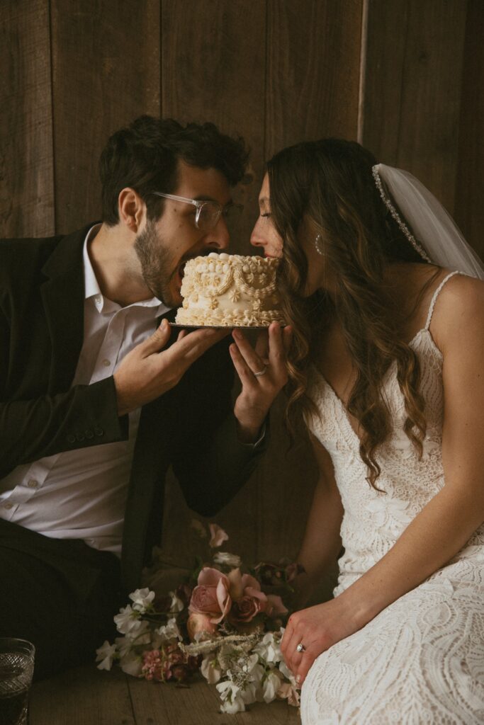 Man and woman in wedding attire eating a small elopement cake with no forks. 