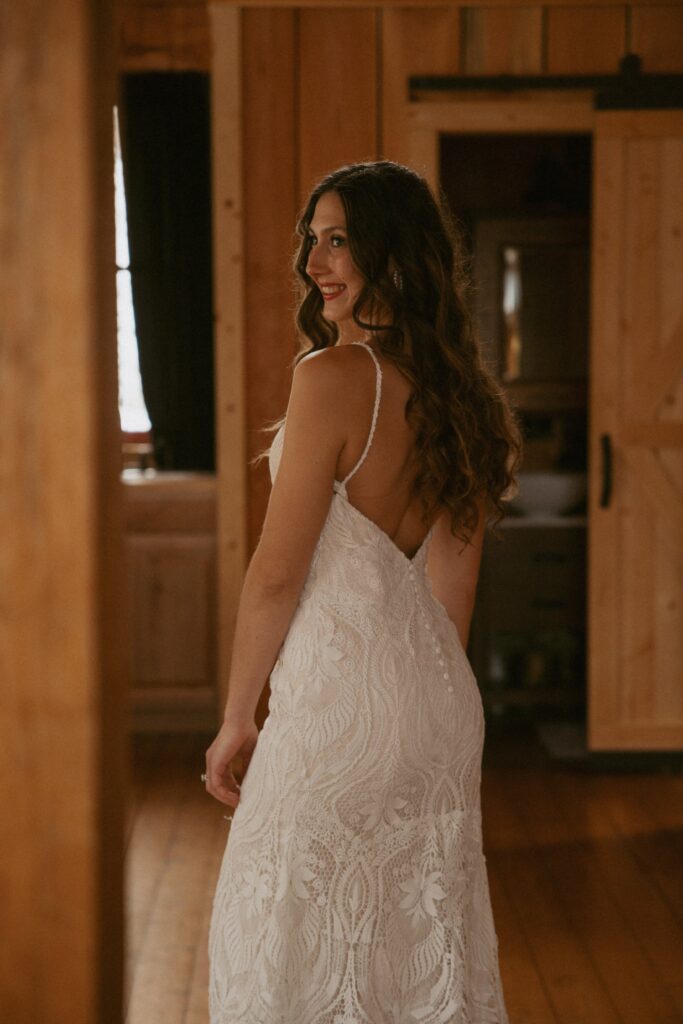 Woman in wedding dress standing in cabin smiling.