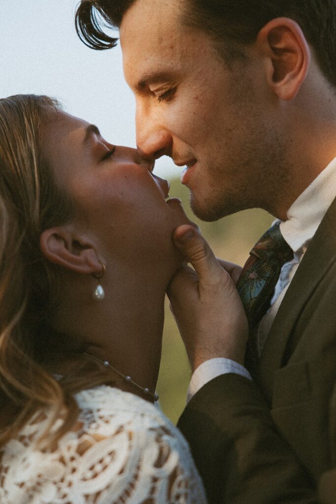 Man and woman in wedding attire going in for a kiss at the main overlook in Cloudland Canyon State park.