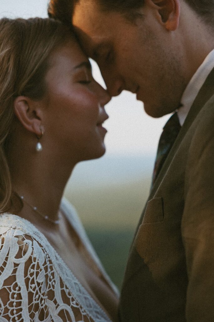 Man and woman in wedding attire going forehead to forehead at the main overlook in Cloudland Canyon State park.