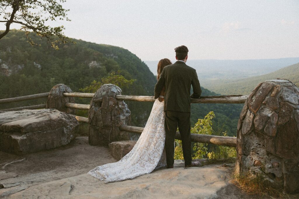 Man and woman in wedding attire looking at mountains at the main overlook in Cloudland Canyon State park.