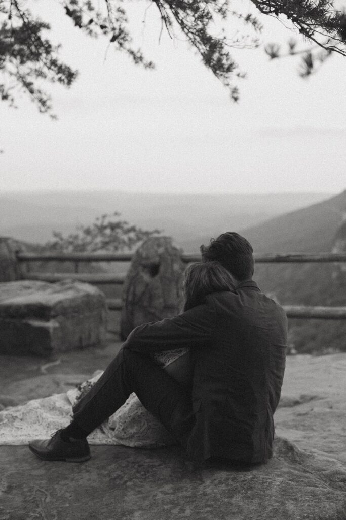 Man and woman in wedding attire sitting on rocks at the main overlook in Cloudland Canyon State park.