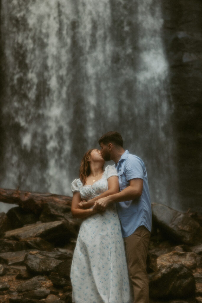 Man and woman kissing in front of Looking Glass Falls.