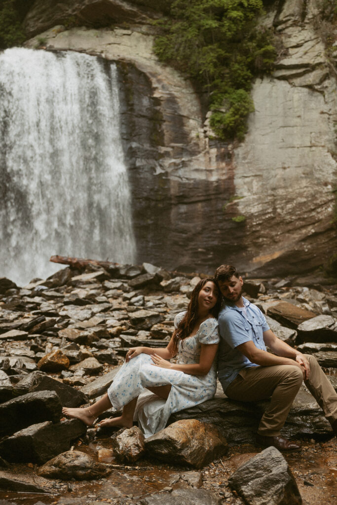 Man and woman sitting on rocks in front of Looking Glass Falls.