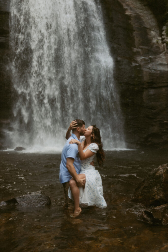 Man and woman kissing in front of Looking Glass Falls.