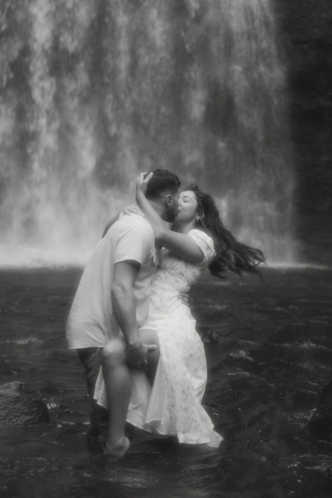 Man and woman kissing in front of Looking Glass Falls.