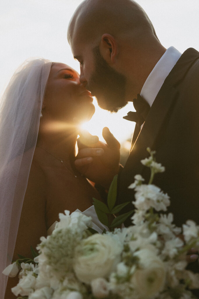 Man pulling woman in for a kiss with sun shining through.