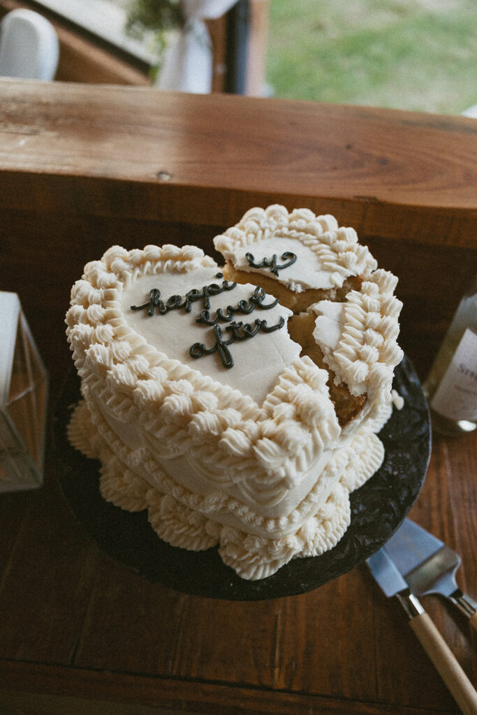 A small heart shaped wedding cake with "happily ever after" written on it.