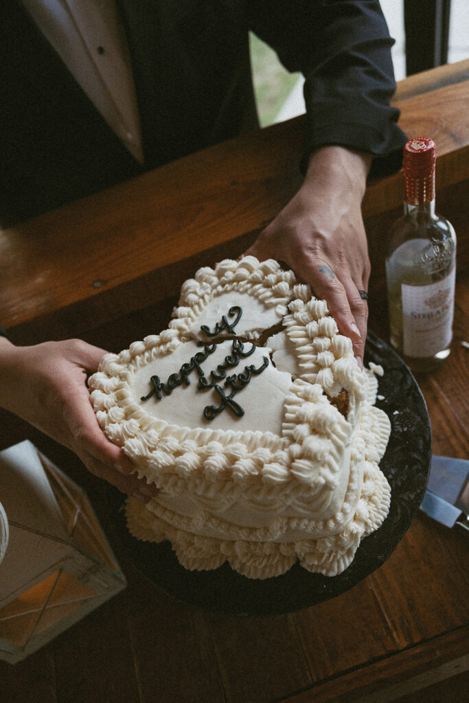 Man in suit holding a small wedding cake together that had cracked.