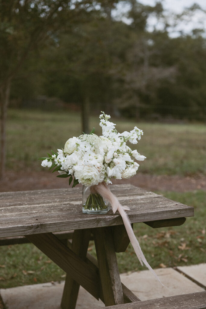 White wedding floral bouquet sitting on a picnic table at walker century farms.