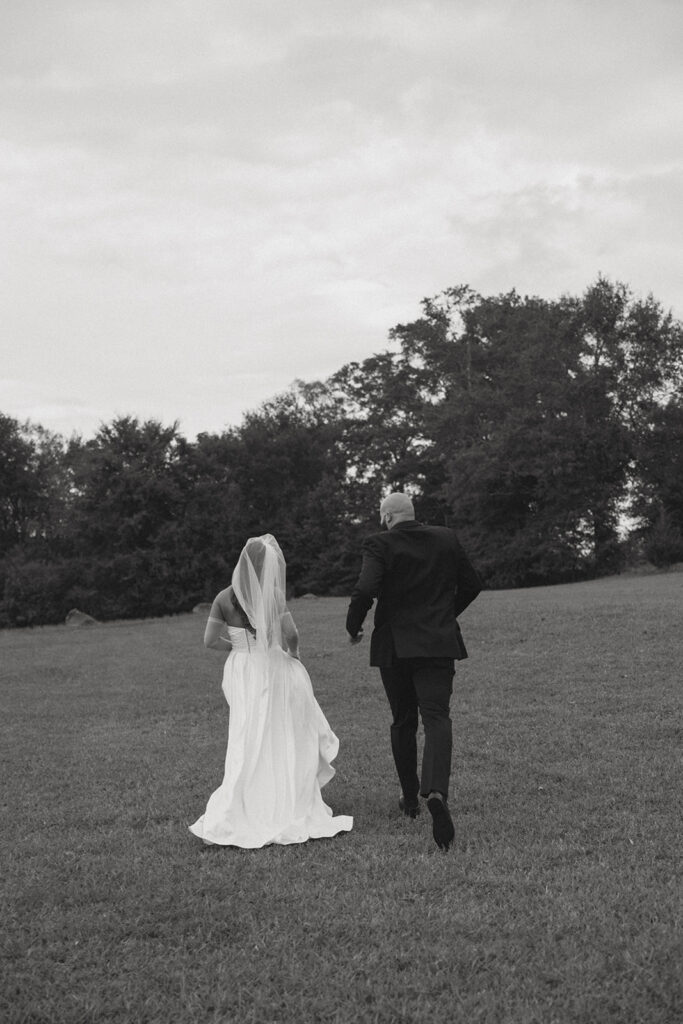 Man and woman in wedding attire running in field at Walker century farms.