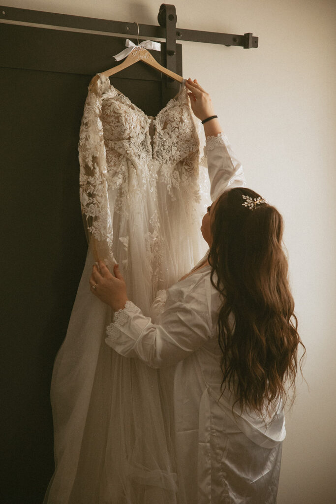 woman getting wedding dress down from back of door