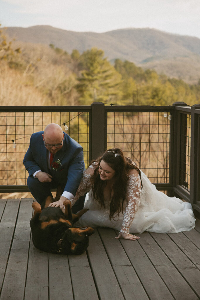 bride and groom petting their dog on airbnb deck in north georgia mountains during their elopement