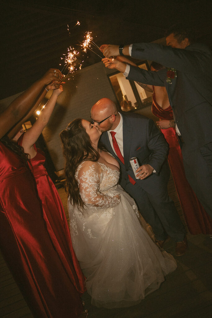 bride and groom walking through sparkler arch made by their bridal party