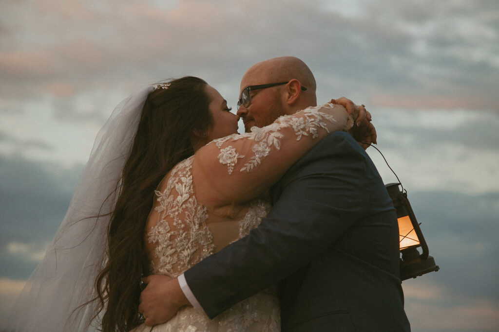 Man and woman in wedding attire, holding lanterns at sunset in the north georgia mountains