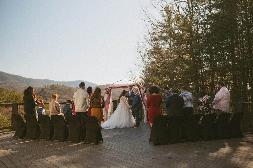 wedding on the deck at an airbnb with the mountains behind them