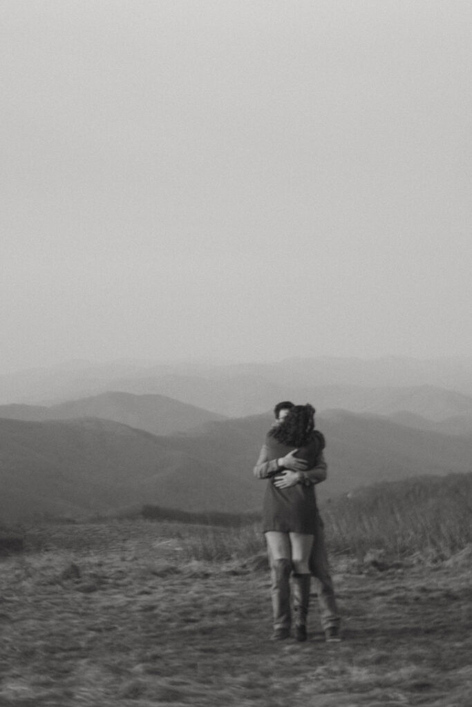 Man and woman hugging during engagement photos at Max Patch mountain in North Carolina.