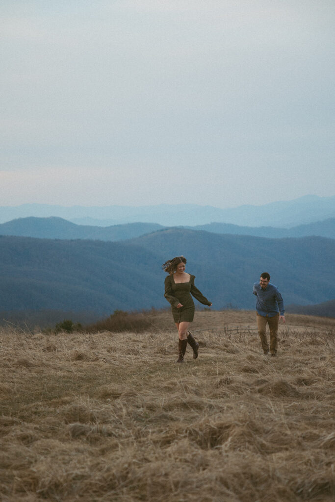 Man chasing woman during engagement photos at Max Patch mountain in North Carolina.