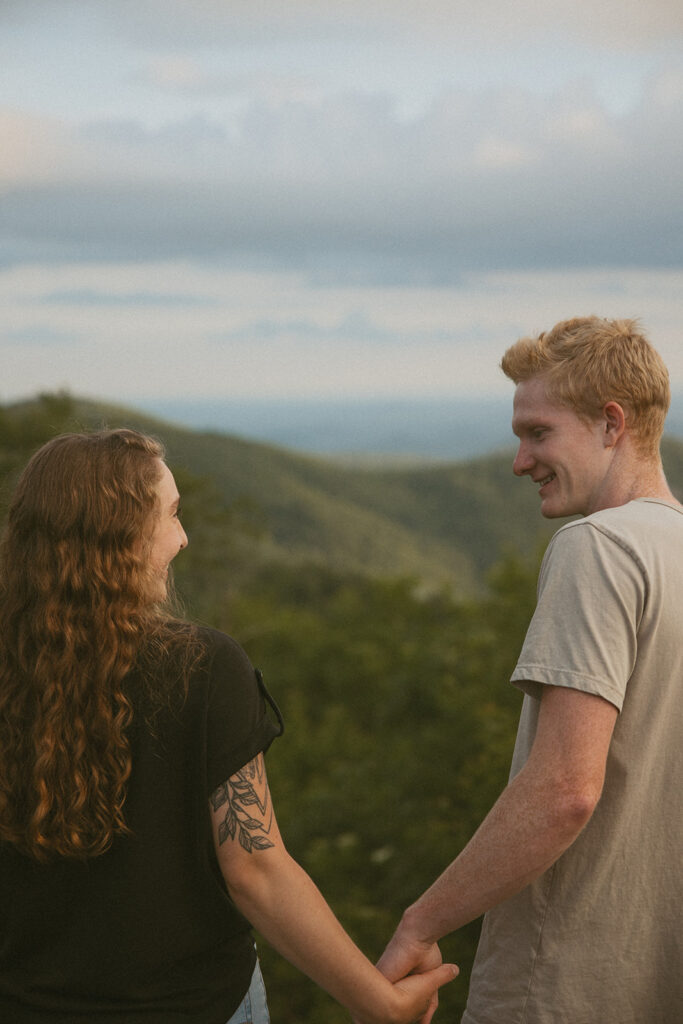 Man and woman holding hands and smiling at each other at Sassafras Mountain.