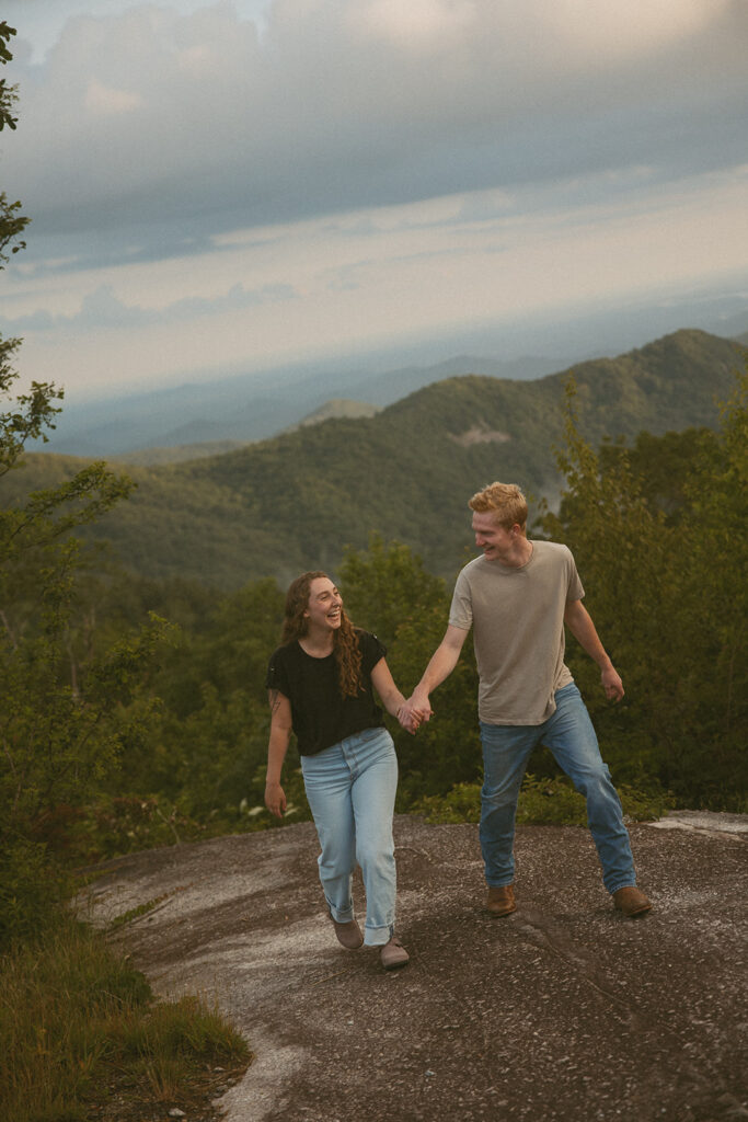Man and woman holding hands while standing on a rock at Sassafras Mountain.