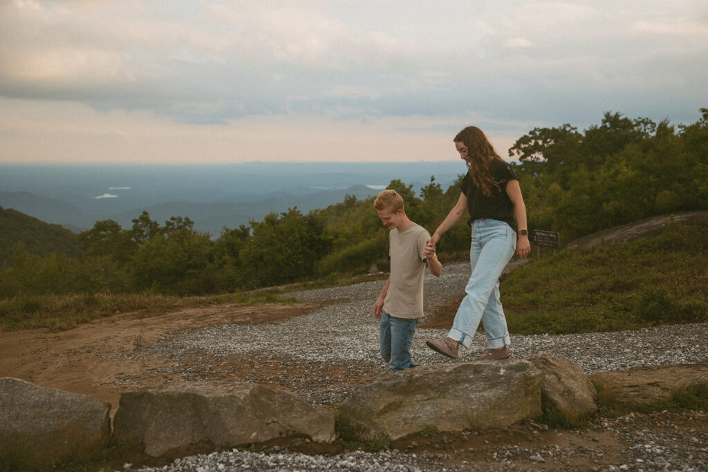 Man helping woman walk across rocks at Sassafras Mountain.