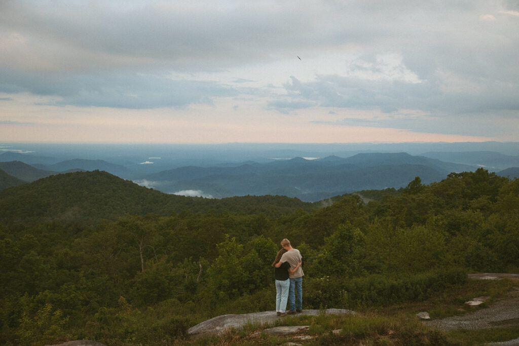 Man and woman hugging while standing on a rock at Sassafras Mountain.