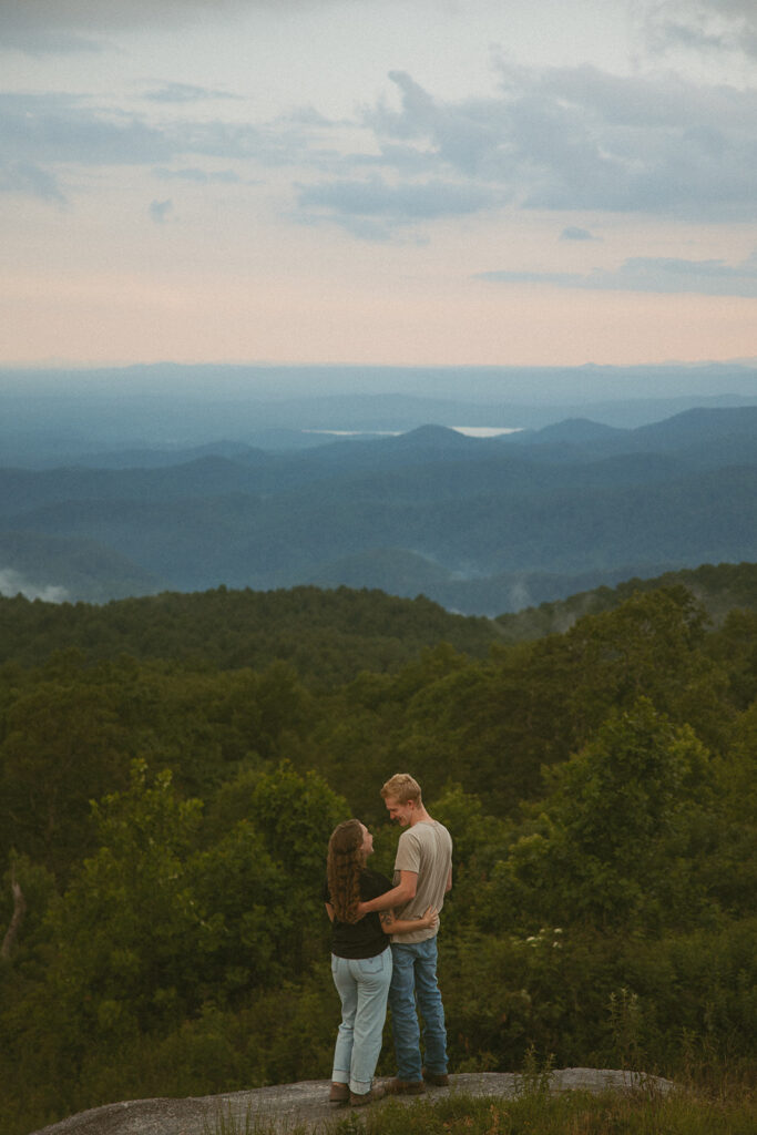 Man and woman looking at each other while standing on a rock at Sassafras Mountain.