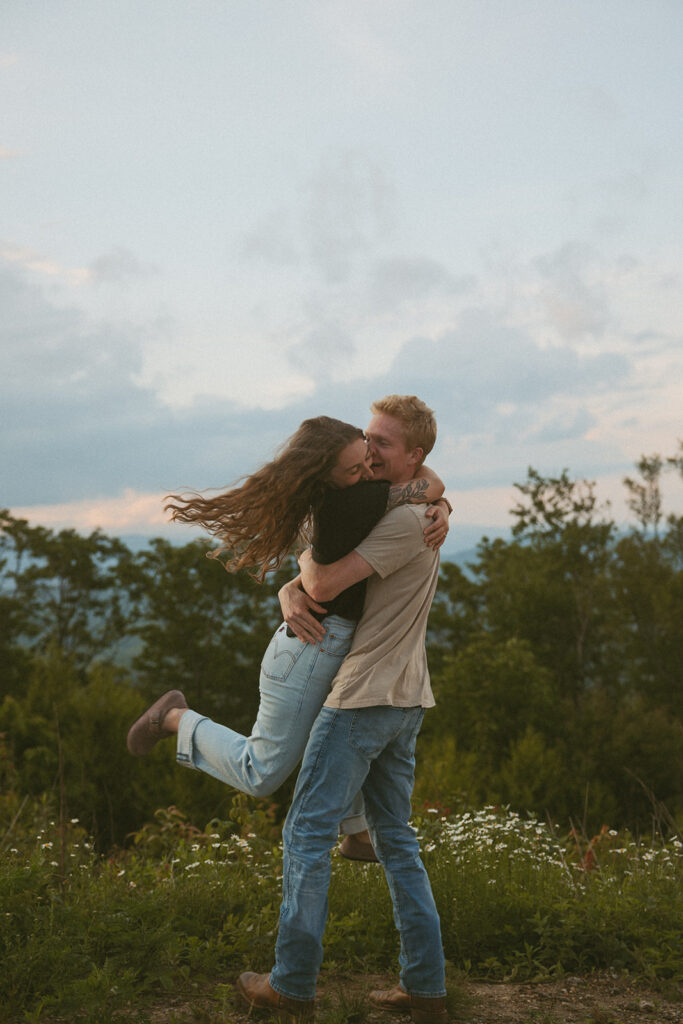 Man spinning woman with flowers and mountains behind them at Sassafras Mountain.