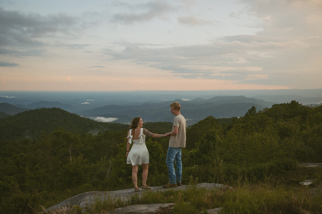 Man and woman holding hands while standing on a rock at Sassafras Mountain.