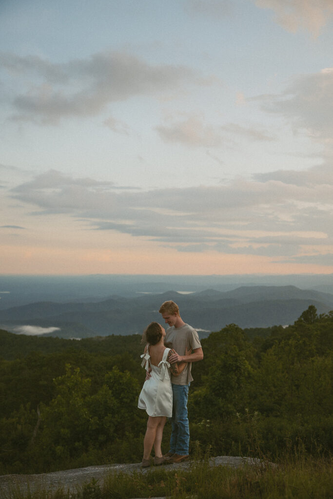 Man and woman hugging while standing on a rock at Sassafras Mountain.