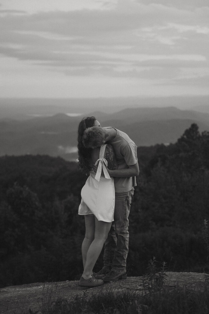 Man kissing womans neck while standing on a rock at Sassafras Mountain.