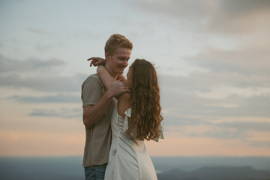 Man and woman hugging with sky behind them at Sassafras Mountain.