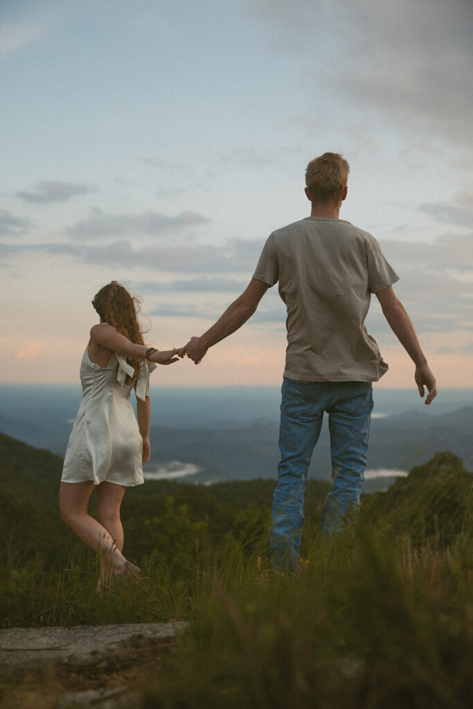 Man and woman holding hands while standing on a rock at Sassafras Mountain.