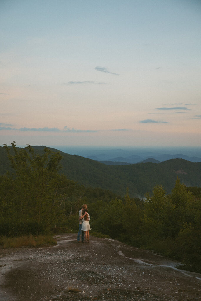 Man and woman hugging while standing on a rock at Sassafras Mountain.