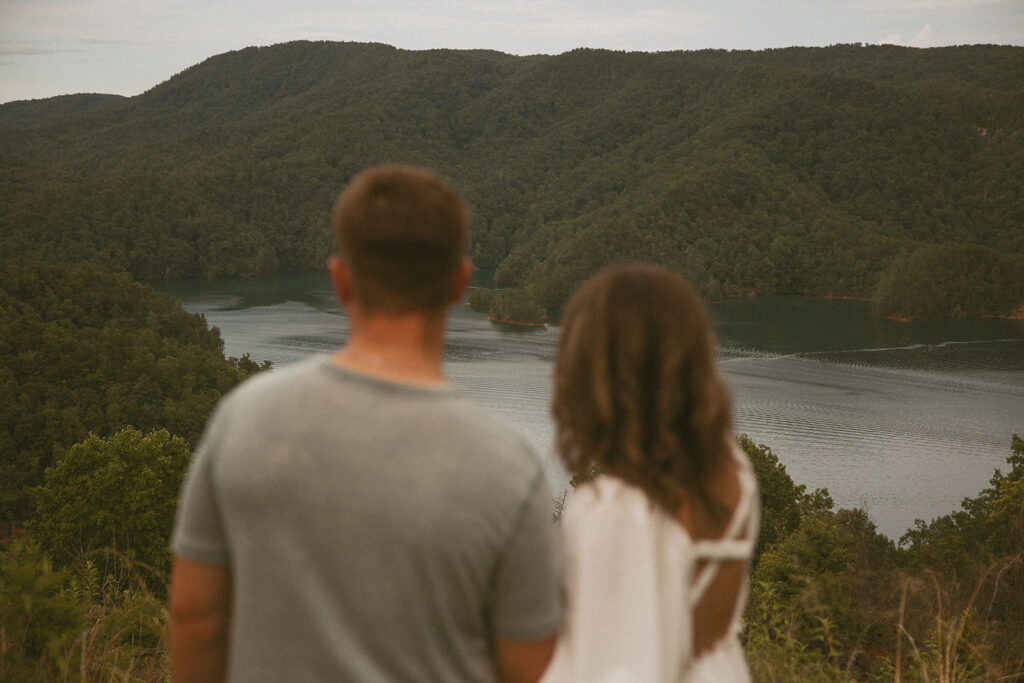 Man and woman looking at mountains and lake with the mountains in focus