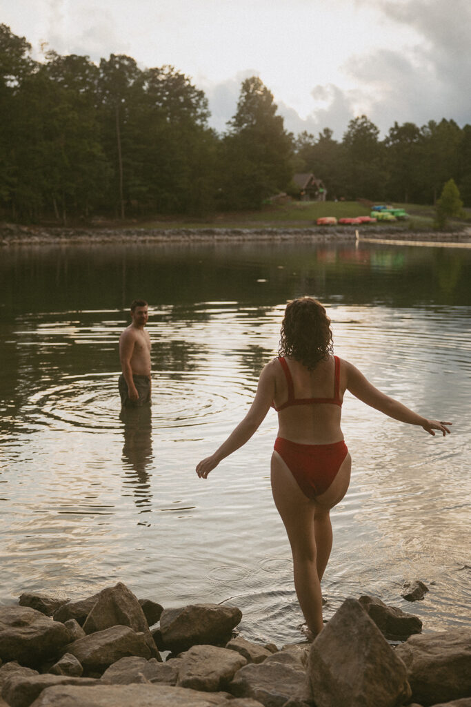 Woman walking on rocks and looking at a man swimming
