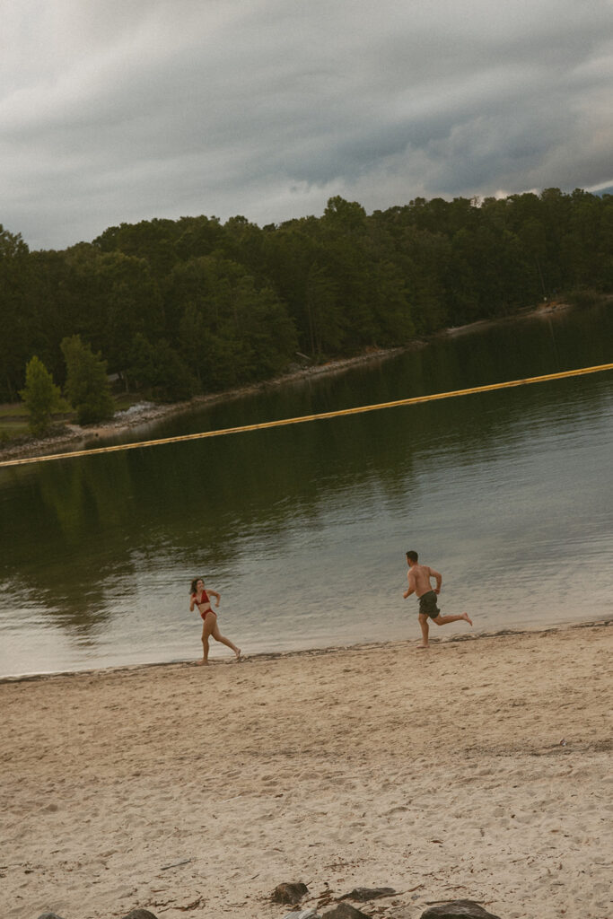man chasing a woman on the lake beach