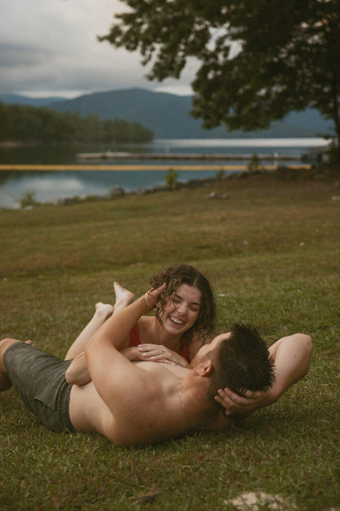 man and woman in swimsuits laying on the grass and laughing