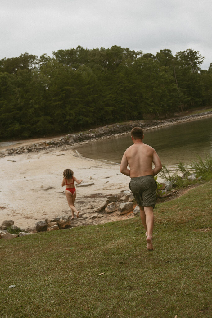 man and woman running into the lake wearing swimsuits