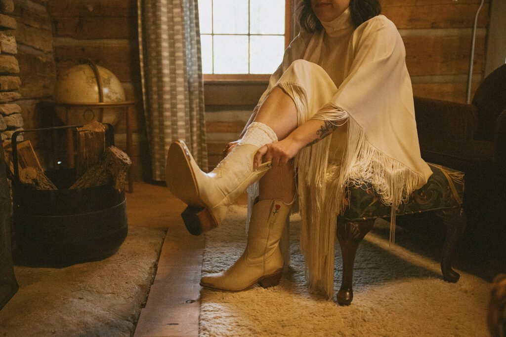 woman sliding on white boots for her elopement